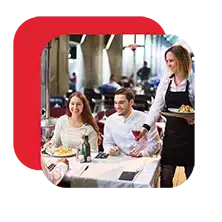 Waitress serving food to a couple dining at a restaurant table.